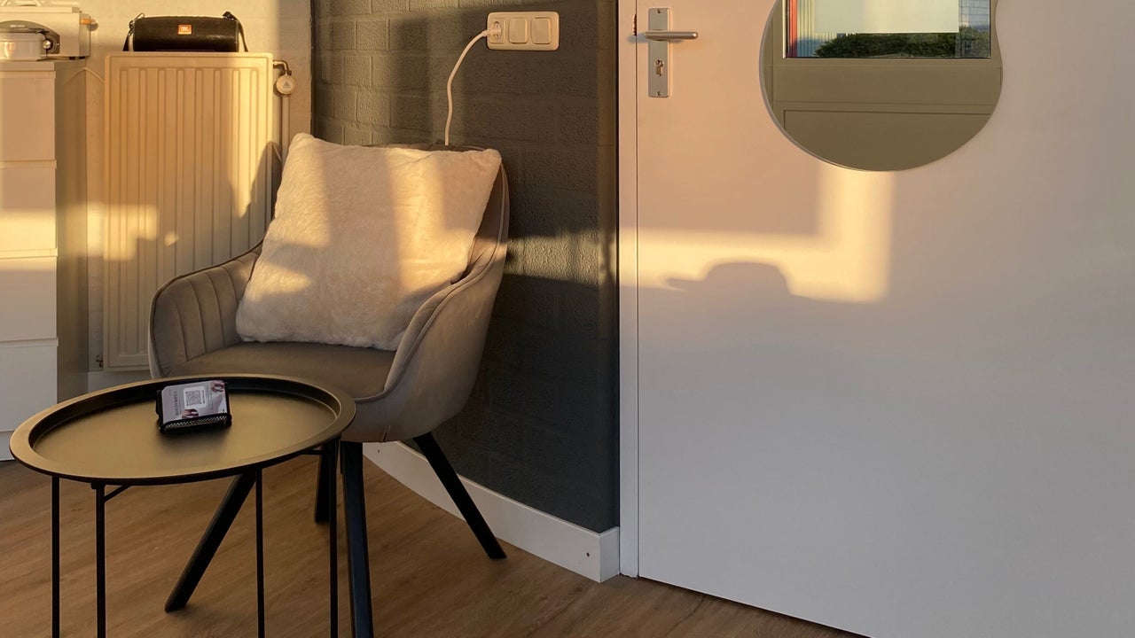 Grijze fauteuil met een kussen en een rond bijzettafeltje in de salon